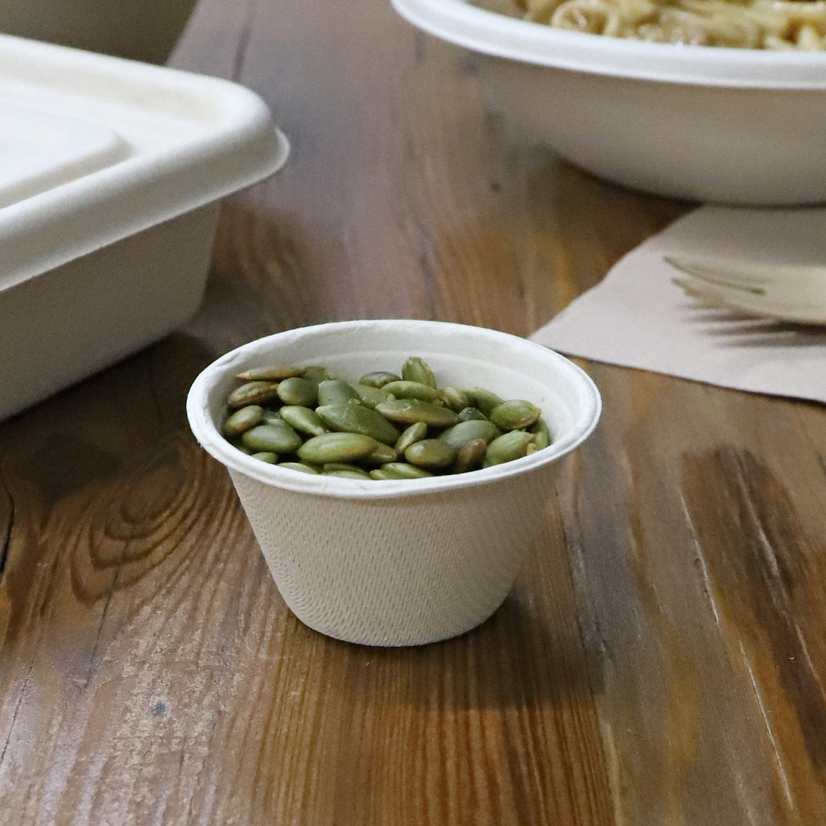 World Centric 2 oz Fiber Souffle Cup shown with pumpkin seeds.